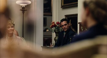 Movie still from “The Master” (2012), directed by Paul Thomas Anderson – A man sitting in front of a vase of flowers; Medium shot, Over the shoulder angle