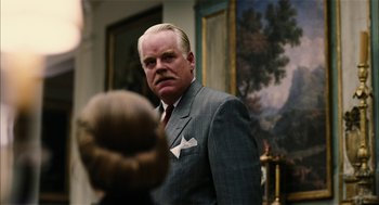 Movie still from “The Master” (2012), directed by Paul Thomas Anderson – A man in a suit and tie looking at the camera; Close Up shot, Over the shoulder angle