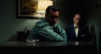 Movie still from “The Master” (2012), directed by Paul Thomas Anderson – A man sitting at a table in a dark room; Medium shot, Over the shoulder angle