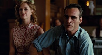 Movie still from “The Master” (2012), directed by Paul Thomas Anderson – A man and a woman sitting next to each other in a room; Medium shot, Over the shoulder angle