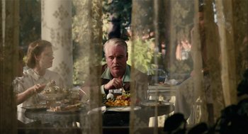 Movie still from “The Master” (2012), directed by Paul Thomas Anderson – A man sitting at a table with food in front of him; Medium shot, Over the shoulder angle
