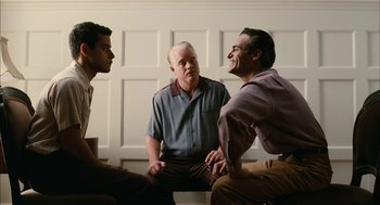 Movie still from “The Master” (2012), directed by Paul Thomas Anderson – A group of men sitting next to each other in front of a white wall; Medium shot, Over the shoulder angle