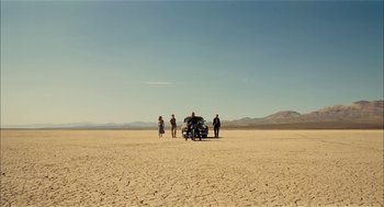 Movie still from “The Master” (2012), directed by Paul Thomas Anderson – A group of people standing in the desert near a car; Extreme Wide shot, High angle