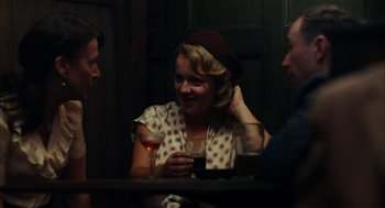 Movie still from “The Master” (2012), directed by Paul Thomas Anderson – A woman sitting at a table holding a glass of wine; Medium shot, Over the shoulder angle