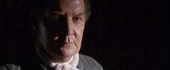 Movie still from “The Mission” (1986), directed by Roland Joffé – An older man with a white shirt and a white tie; Close Up shot, Low angle