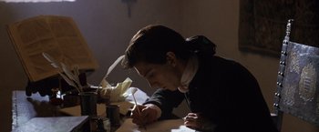 Movie still from “The Mission” (1986), directed by Roland Joffé – A man writing on a piece of paper with a quill pen; Medium shot, Over the shoulder angle