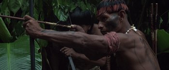 Movie still from “The Mission” (1986), directed by Roland Joffé – A man with a bow and arrow in the woods; Medium shot, Low angle