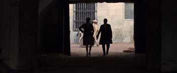 Movie still from “The Mission” (1986), directed by Roland Joffé – Two women are walking down the street in the dark; Wide shot, Low angle