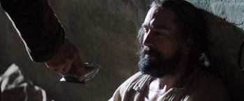 Movie still from “The Mission” (1986), directed by Roland Joffé – A man with a long beard is drinking from a glass; Close Up shot, Low angle