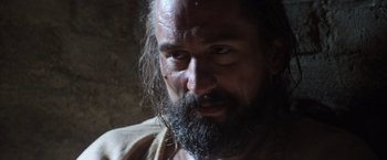 Movie still from “The Mission” (1986), directed by Roland Joffé – A man with a long beard is looking at the camera; Close Up shot, Low angle