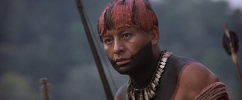 Movie still from “The Mission” (1986), directed by Roland Joffé – A man with a painted face is wearing a necklace; Close Up shot, Low angle