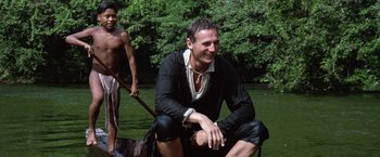 Movie still from “The Mission” (1986), directed by Roland Joffé – A man sitting in a boat on a body of water; Medium shot, Low angle