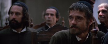 Movie still from “The Mission” (1986), directed by Roland Joffé – Two men sitting in a wooden chair in a room; Close Up shot, Over the shoulder angle