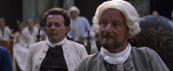 Movie still from “The Mission” (1986), directed by Roland Joffé – A man in a wig and a wig stands next to another man in a wig; Close Up shot, Over the shoulder angle