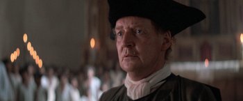 Movie still from “The Mission” (1986), directed by Roland Joffé – An old man wearing a black hat in a room; Close Up shot, Low angle