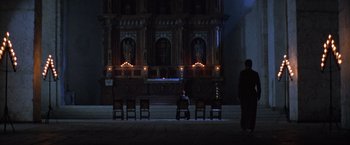 Movie still from “The Mission” (1986), directed by Roland Joffé – A man standing in front of an alter with candles; Extreme Wide shot, High angle