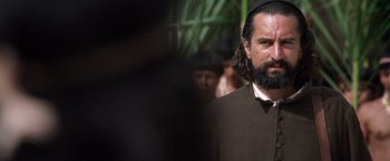 Movie still from “The Mission” (1986), directed by Roland Joffé – A man with a long beard wearing a hat; Close Up shot, Over the shoulder angle