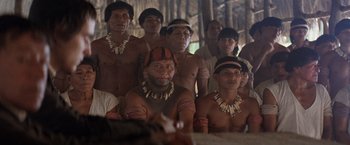 Movie still from “The Mission” (1986), directed by Roland Joffé – A group of people in native dress in front of trees; Wide shot, High angle