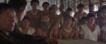 Movie still from “The Mission” (1986), directed by Roland Joffé – A group of people in native dress standing in a room; Medium shot, High angle