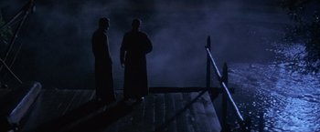 Movie still from “The Mission” (1986), directed by Roland Joffé – Two men standing next to a railing at night; Wide shot, High angle