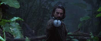 Movie still from “The Mission” (1986), directed by Roland Joffé – A man holding a bow and arrow in the woods; Medium shot, Low angle