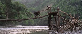 Movie still from “The Mission” (1986), directed by Roland Joffé – A man walking across a bridge over a body of water; Extreme Wide shot, Low angle