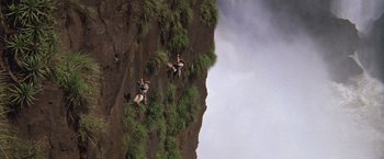 Movie still from “The Mission” (1986), directed by Roland Joffé – Two people climbing a steep rock face on a cloudy day; Extreme Wide shot, High angle