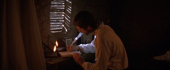 Movie still from “The Mission” (1986), directed by Roland Joffé – A man sitting in front of a laptop computer; Medium shot, High angle