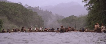 Movie still from “The Mission” (1986), directed by Roland Joffé – A group of people sitting in a boat on a body of water; Extreme Wide shot, High angle
