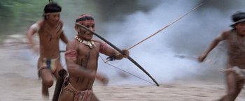 Movie still from “The Mission” (1986), directed by Roland Joffé – A man is holding a bow and arrow in the sand; Medium shot, Low angle