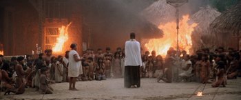 Movie still from “The Mission” (1986), directed by Roland Joffé – A group of people standing in front of a burning building; Extreme Wide shot, High angle