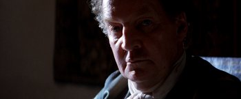 Movie still from “The Mission” (1986), directed by Roland Joffé – An older man wearing a white shirt and a blue tie; Close Up shot, Over the shoulder angle