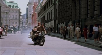 Movie still from “The Motorcycle Diaries” (2004), directed by Walter Salles – Two people riding a motorcycle down a street; Wide shot, High angle
