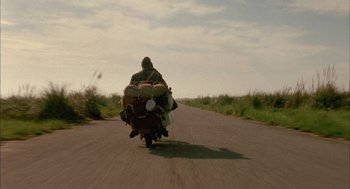 Movie still from “The Motorcycle Diaries” (2004), directed by Walter Salles – A man riding a motorcycle down the middle of a road; Wide shot, Low angle