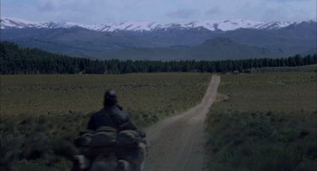 Movie still from “The Motorcycle Diaries” (2004), directed by Walter Salles – A man riding a motorcycle down a dirt road; Extreme Wide shot, Over the shoulder angle
