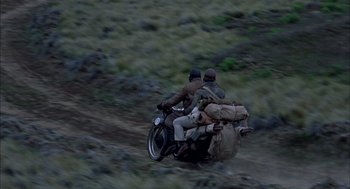 Movie still from “The Motorcycle Diaries” (2004), directed by Walter Salles – Two men riding a motorcycle down a dirt road; Wide shot, High angle
