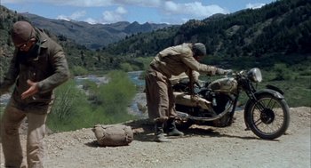 Movie still from “The Motorcycle Diaries” (2004), directed by Walter Salles – A man on a motorcycle on a dirt road near a river; Wide shot, High angle