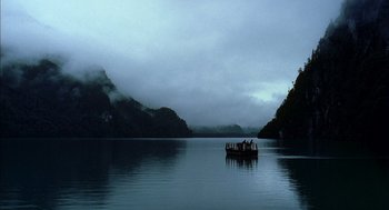 Movie still from “The Motorcycle Diaries” (2004), directed by Walter Salles – A boat floating on a body of water near mountains; Extreme Wide shot, High angle