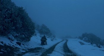 Movie still from “The Motorcycle Diaries” (2004), directed by Walter Salles – A person riding a motorcycle on a snowy road; Extreme Wide shot, High angle