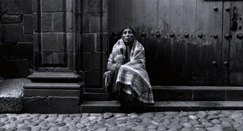 Movie still from “The Motorcycle Diaries” (2004), directed by Walter Salles – An older woman sitting on steps with a blanket over her head; Wide shot, High angle