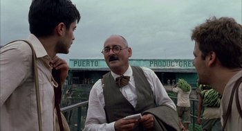 Movie still from “The Motorcycle Diaries” (2004), directed by Walter Salles – A man in a bow tie talking to another man in a vest; Medium shot, Over the shoulder angle