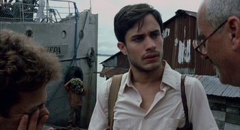 Movie still from “The Motorcycle Diaries” (2004), directed by Walter Salles – A man with a beard and a white shirt is standing in front of a boat; Close Up shot, Over the shoulder angle