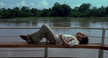 Movie still from “The Motorcycle Diaries” (2004), directed by Walter Salles – A man laying on top of a bench near a body of water; Wide shot, Low angle
