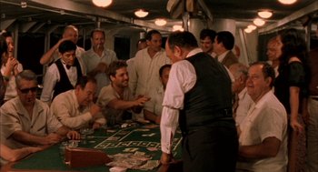 Movie still from “The Motorcycle Diaries” (2004), directed by Walter Salles – A group of men standing around a table with cards on it; Wide shot, High angle