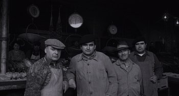 Movie still from “The Motorcycle Diaries” (2004), directed by Walter Salles – A black and white photo of a group of men in hats and aprons; Medium shot, High angle
