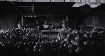 Movie still from “The Motorcycle Diaries” (2004), directed by Walter Salles – Three people are standing in front of a table full of tomatoes; Wide shot, Low angle