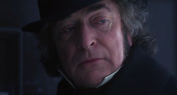 Movie still from “The Muppet Christmas Carol” (1992), directed by Brian Henson – An older man wearing a black hat and a black coat; Close Up shot, Low angle