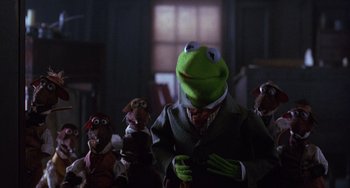 Movie still from “The Muppet Christmas Carol” (1992), directed by Brian Henson – A group of muppets standing next to each other in a dark room; Medium shot, Over the shoulder angle