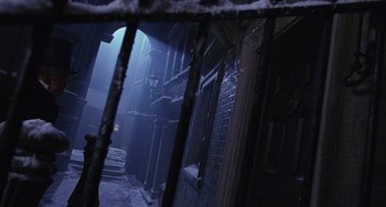 Movie still from “The Muppet Christmas Carol” (1992), directed by Brian Henson – A dark alley with a lamp post and a door way; Wide shot, High angle