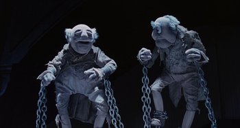 Movie still from “The Muppet Christmas Carol” (1992), directed by Brian Henson – A couple of statues that are chained to each other; Medium shot, Low angle
